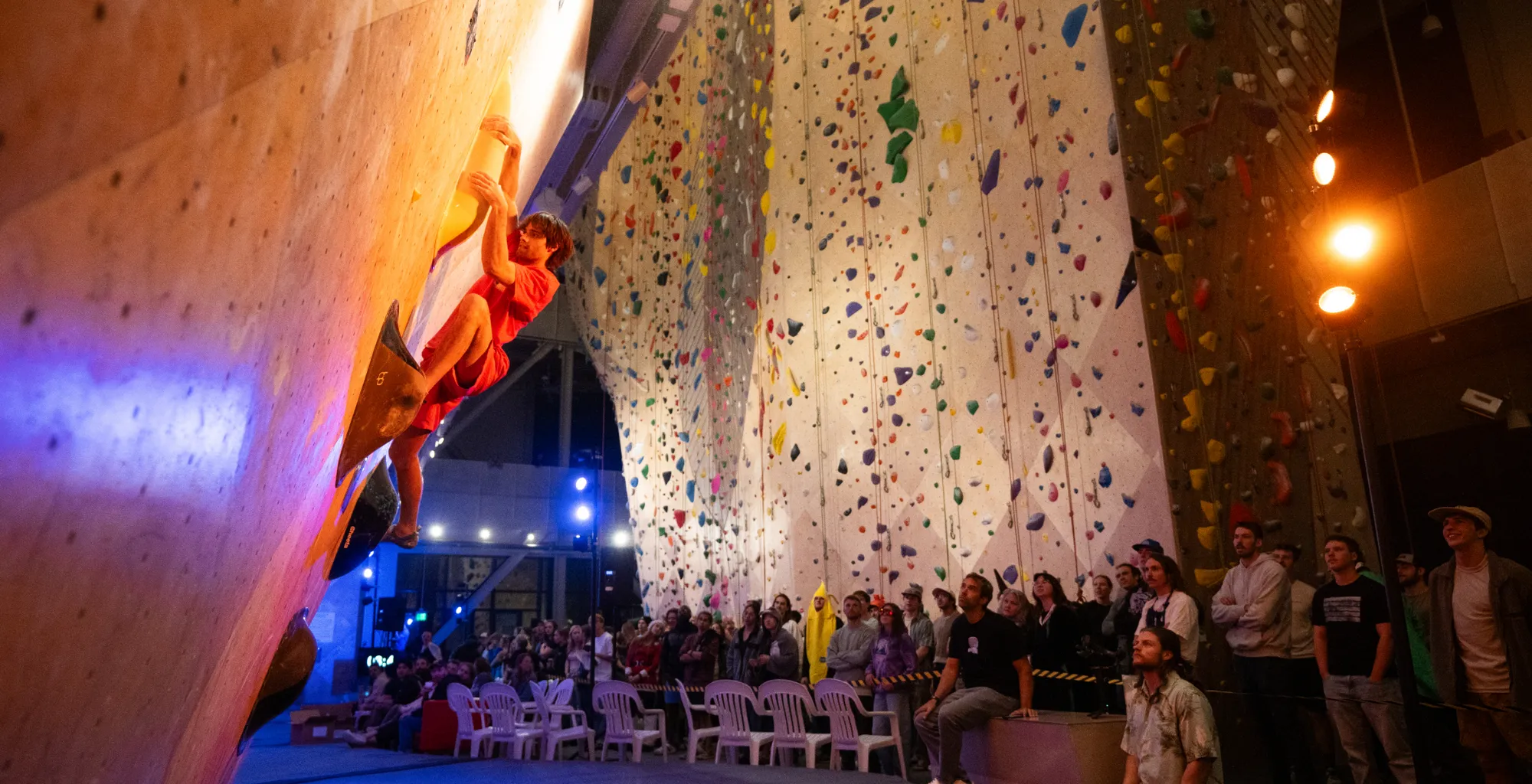 A climber competing on a birch climbing wall in front of a crowd