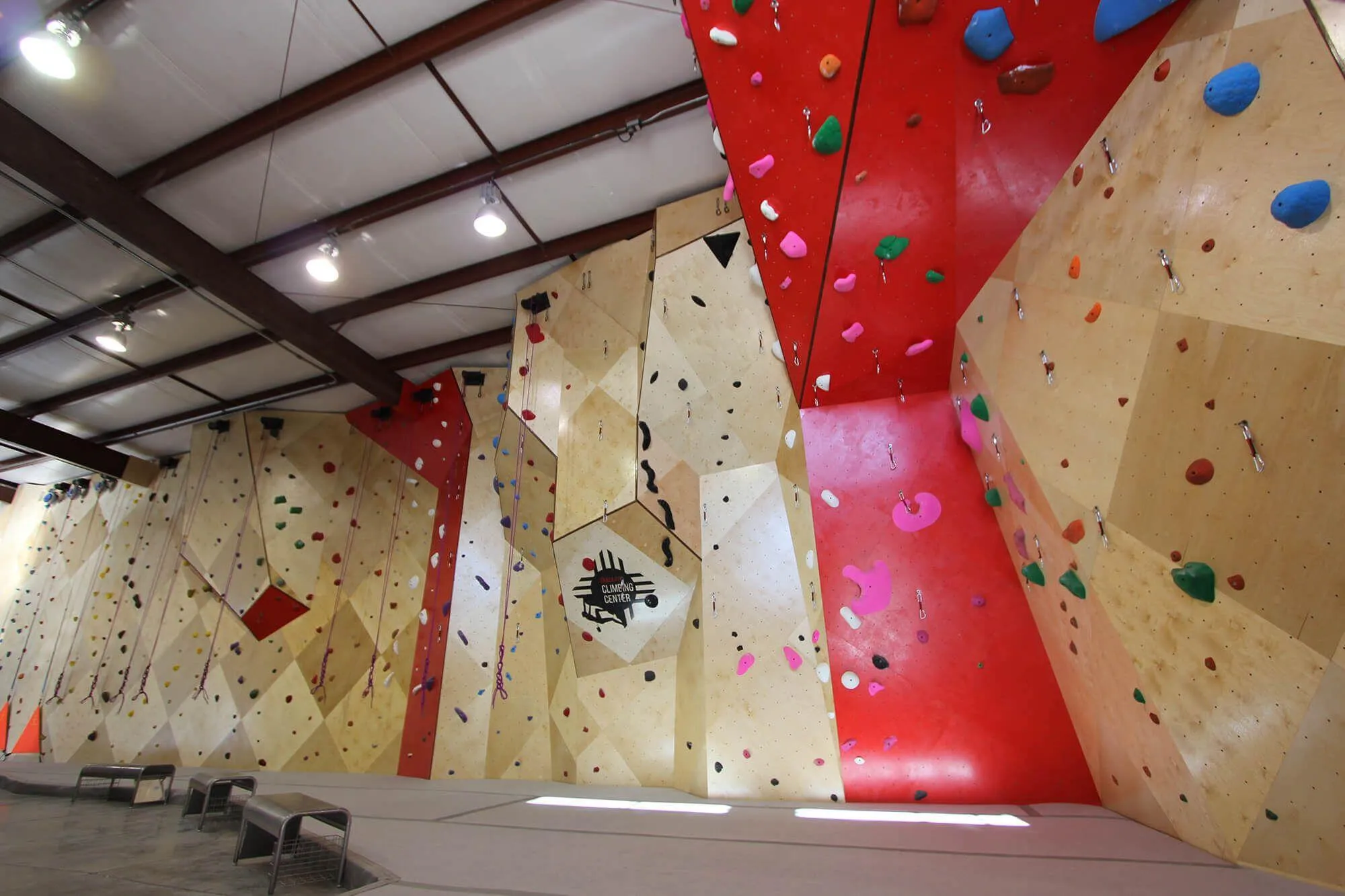 This indoor climbing gym uses a plethora of surface changes in its MLM wall design to visually create depth and intrigue amongst climbers old and new. Surface changes are complimented with custom colors, on-brand for the gym including a custom logo front and center.