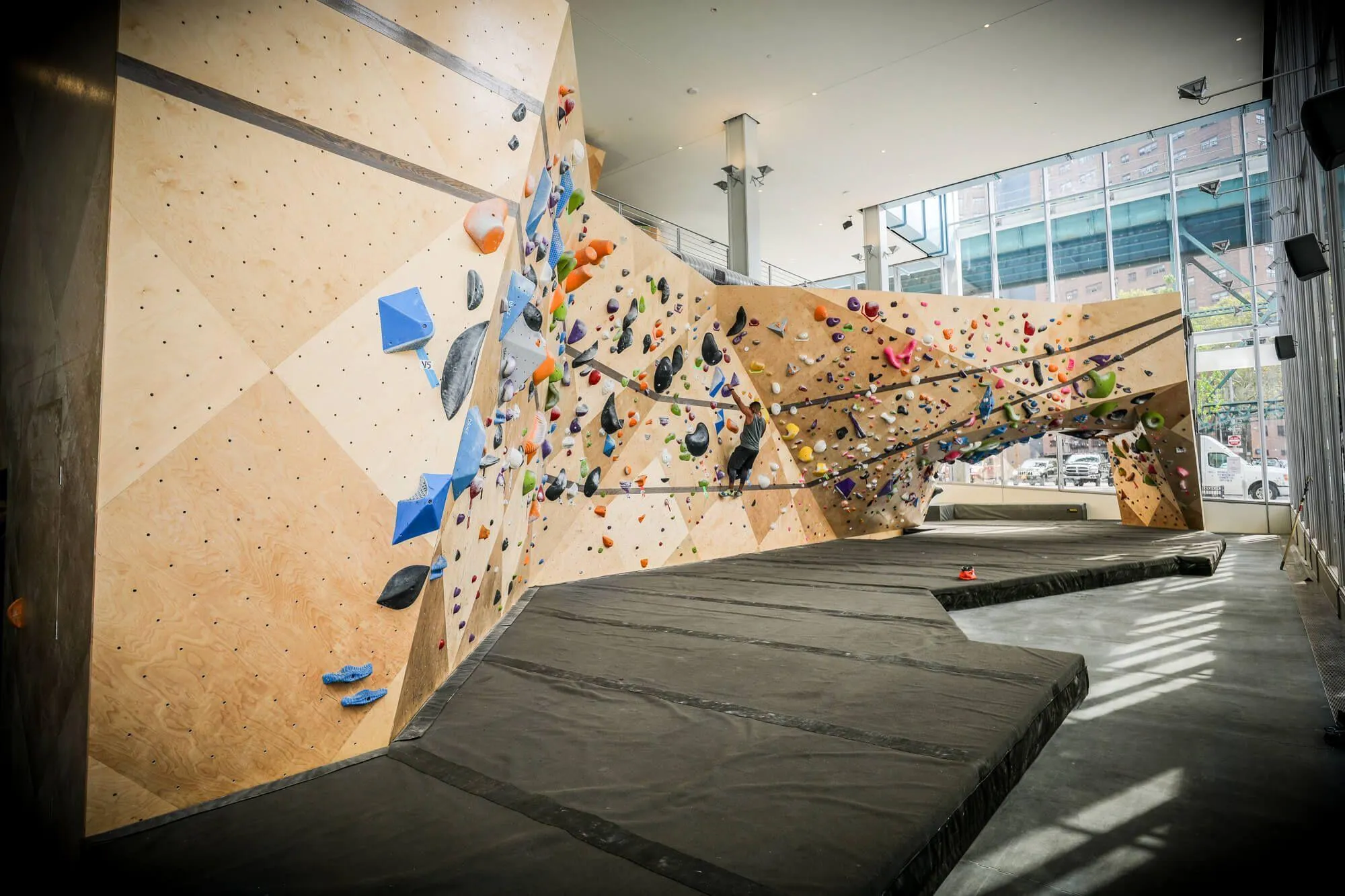 The length of this lower bouldering area is impressive even before you consider how much capacity the cave and backside also add for indoor climbers. Two hardwood stripe details carry the entire length of the walls and help accentuate the climbing wall features.